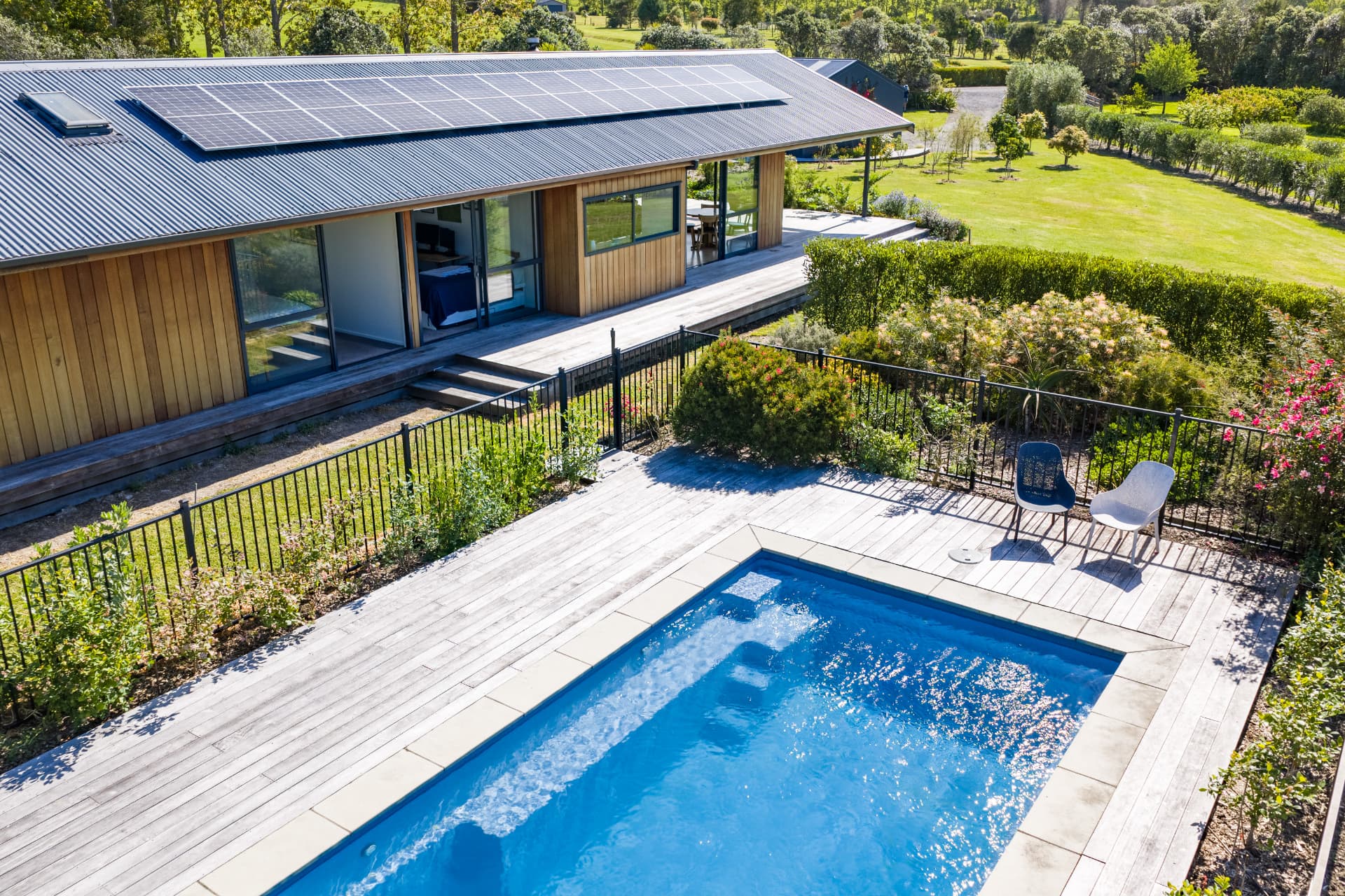 Aerial view of a modern home with swimming pool and rural Mangawhai views
